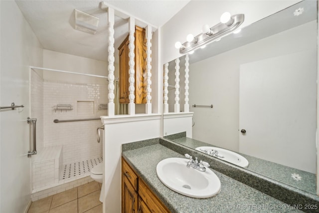 full bathroom featuring toilet, vanity, tiled shower, and tile patterned floors