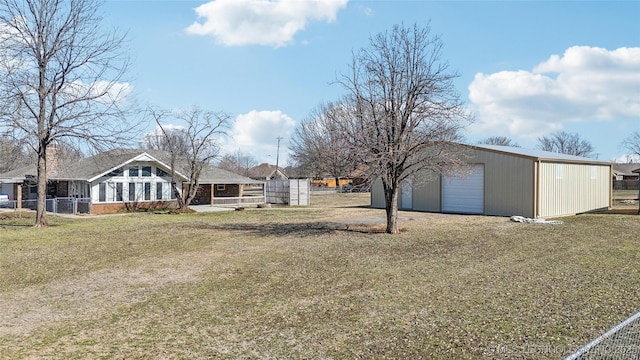 view of yard featuring a garage, driveway, an outdoor structure, and fence