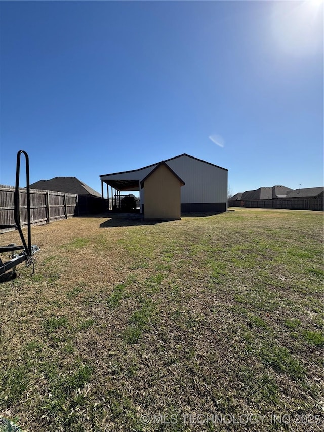 view of yard with an outbuilding, a carport, and fence