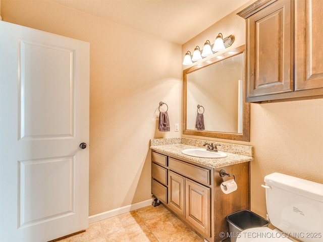 bathroom featuring toilet, vanity, and baseboards