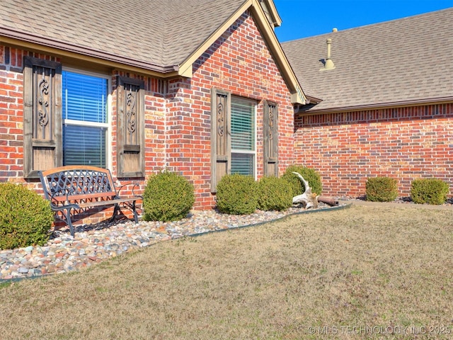 doorway to property with a shingled roof and brick siding