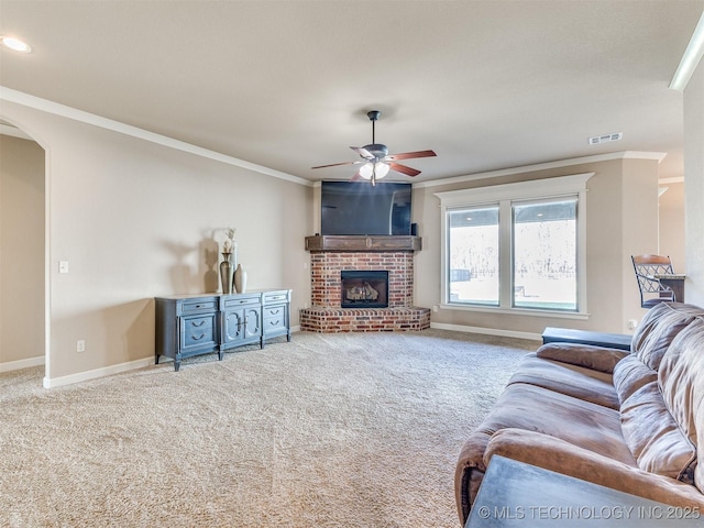 carpeted living room featuring arched walkways, visible vents, baseboards, ornamental molding, and a brick fireplace