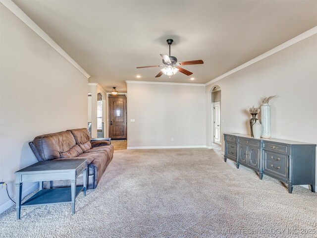 living area with light carpet, baseboards, arched walkways, ceiling fan, and crown molding