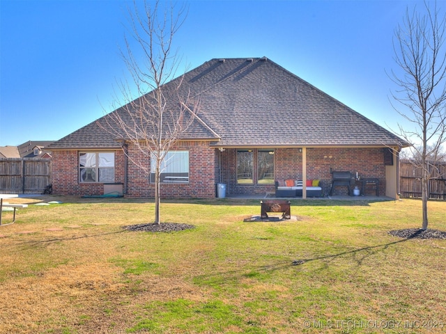 back of house with a yard, a shingled roof, fence, and brick siding