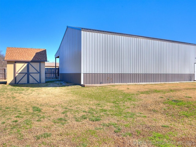 exterior space with a pole building, fence, a lawn, and an outdoor structure