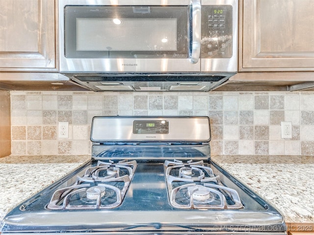 interior details with light stone countertops, stainless steel appliances, and decorative backsplash