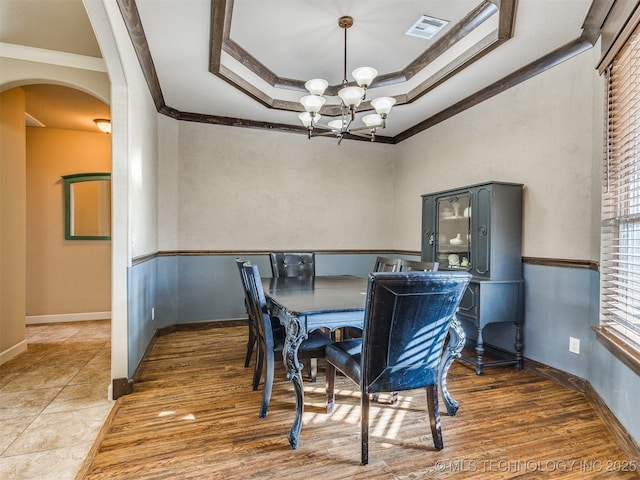 dining area with visible vents, a raised ceiling, arched walkways, crown molding, and a notable chandelier