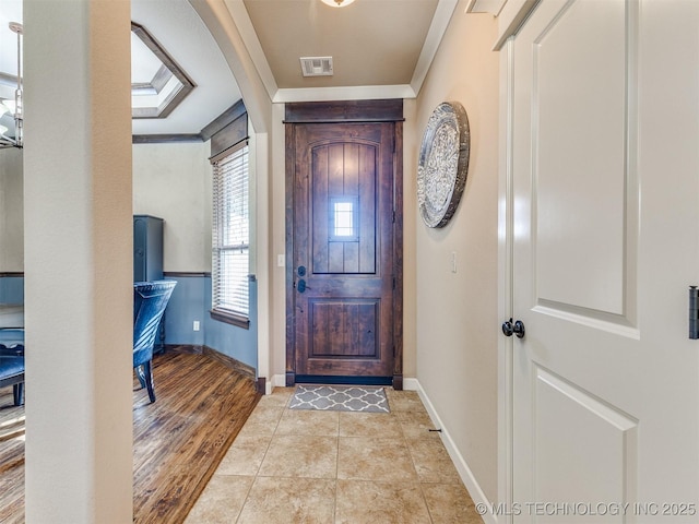 entrance foyer featuring baseboards, light wood-type flooring, visible vents, and crown molding