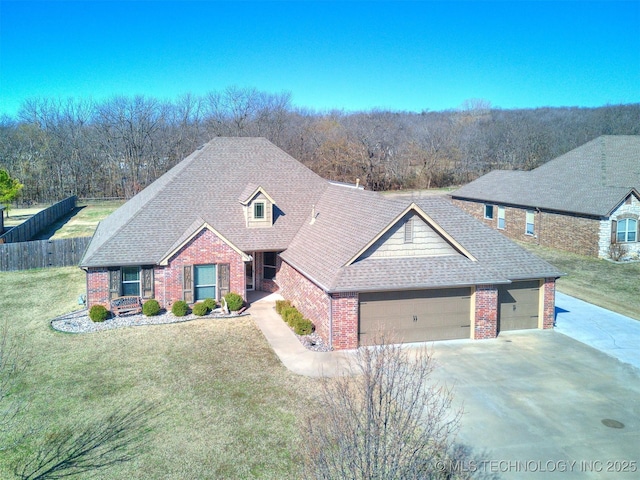 view of front facade with a garage, roof with shingles, fence, a front yard, and brick siding