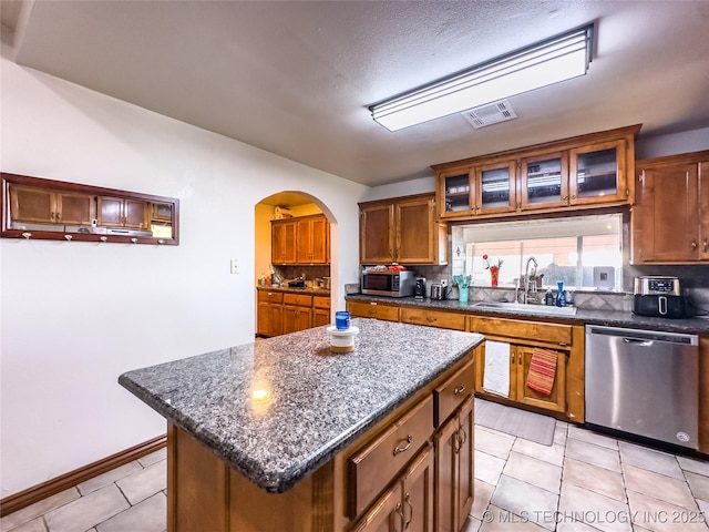 kitchen featuring tasteful backsplash, visible vents, arched walkways, stainless steel appliances, and a sink