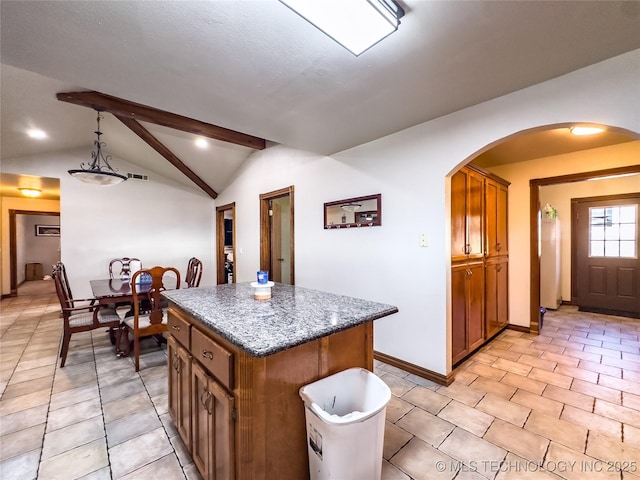 kitchen with arched walkways, light tile patterned floors, vaulted ceiling with beams, a kitchen island, and brown cabinetry