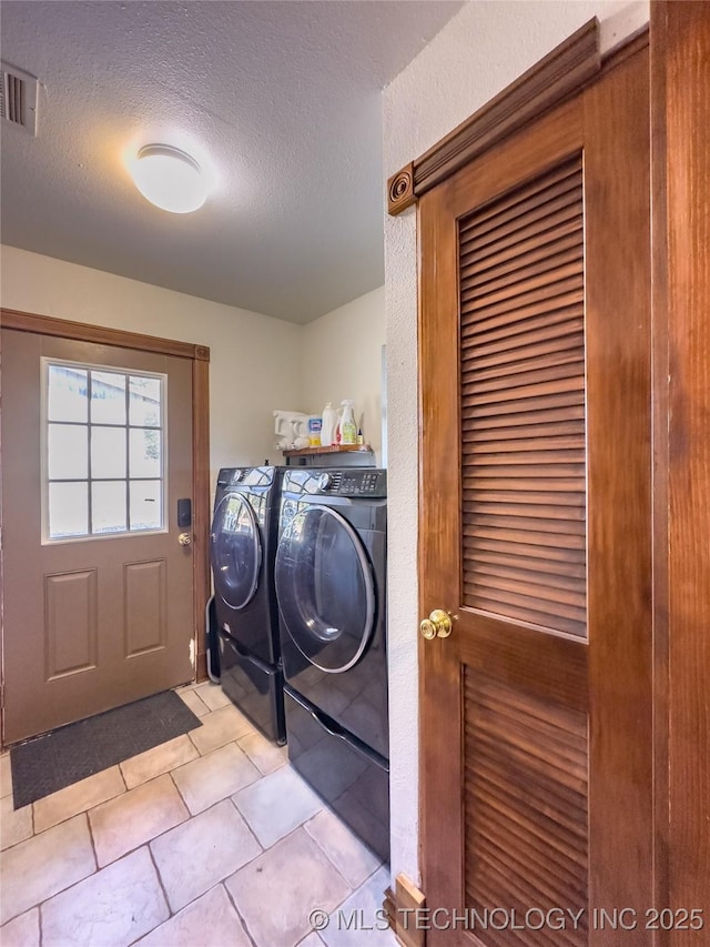 laundry area with laundry area, visible vents, a textured ceiling, and washing machine and clothes dryer