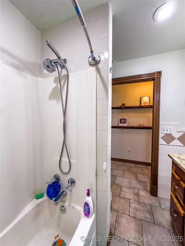 full bath featuring tile patterned flooring, tub / shower combination, vanity, and tile walls