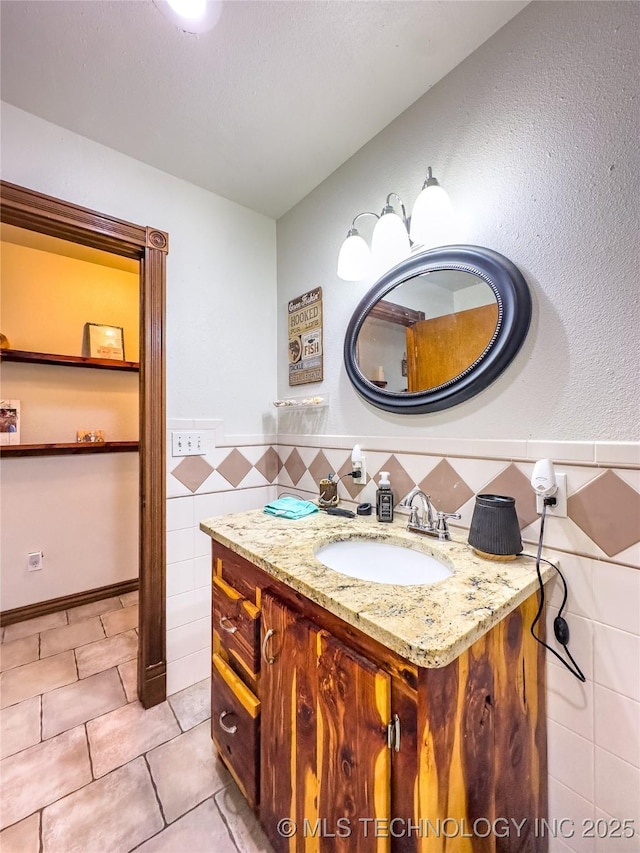 bathroom featuring a wainscoted wall, vanity, tile patterned flooring, and tile walls