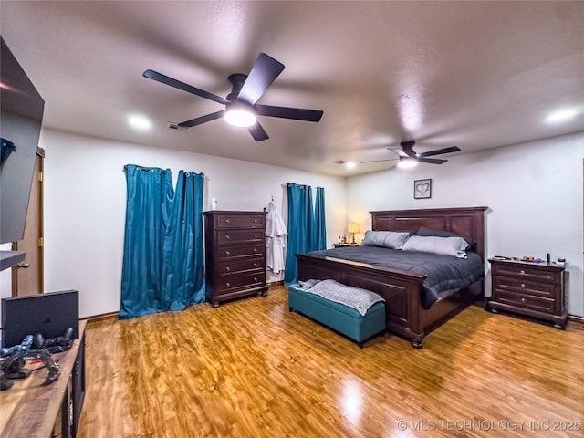 bedroom with ceiling fan, wood finished floors, and visible vents