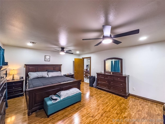 bedroom with baseboards, visible vents, ceiling fan, wood finished floors, and a textured ceiling