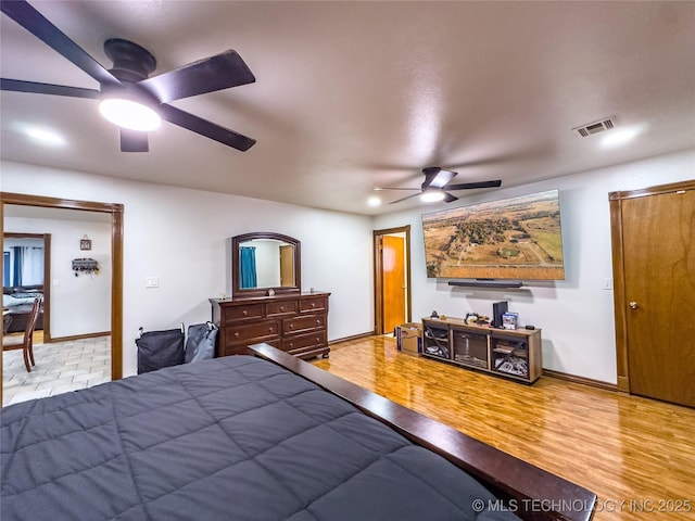 bedroom featuring baseboards, visible vents, ceiling fan, and wood finished floors