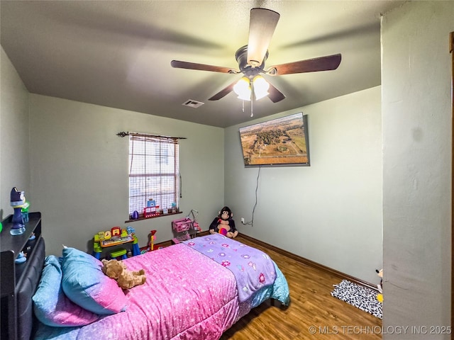 bedroom featuring baseboards, wood finished floors, visible vents, and a ceiling fan