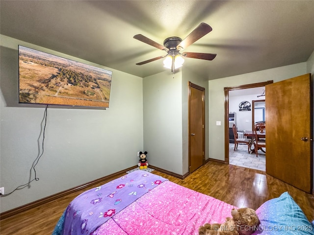 bedroom featuring ceiling fan, baseboards, and wood finished floors