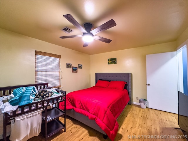 bedroom featuring ceiling fan, wood finished floors, visible vents, and baseboards