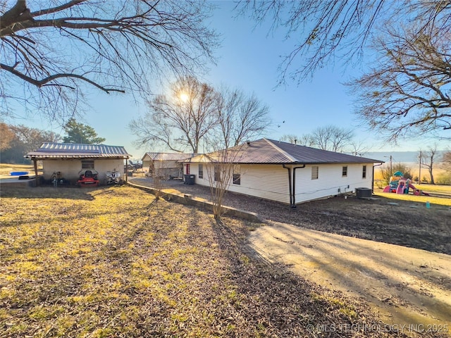 rear view of property with metal roof, central AC, and a playground