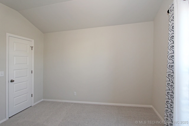 unfurnished room with lofted ceiling, baseboards, and light colored carpet