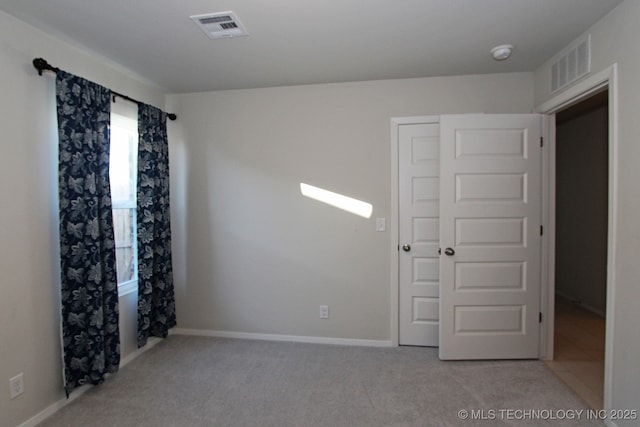 empty room with baseboards, visible vents, and light colored carpet