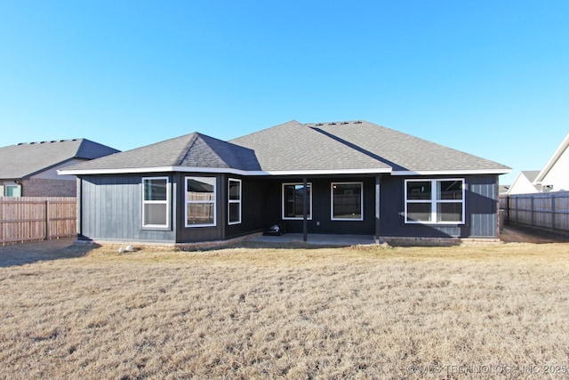 view of front of house with a shingled roof, a fenced backyard, and a front lawn