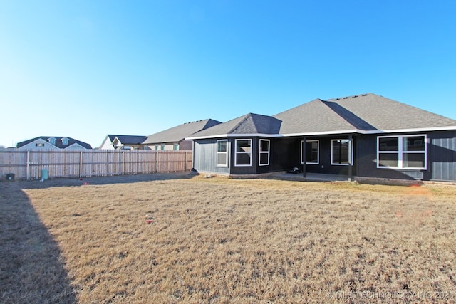 rear view of house with a lawn and fence