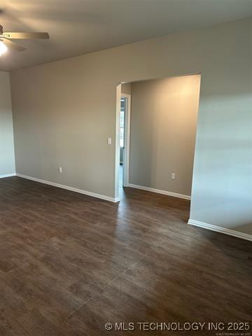 empty room featuring ceiling fan, dark wood-type flooring, and baseboards