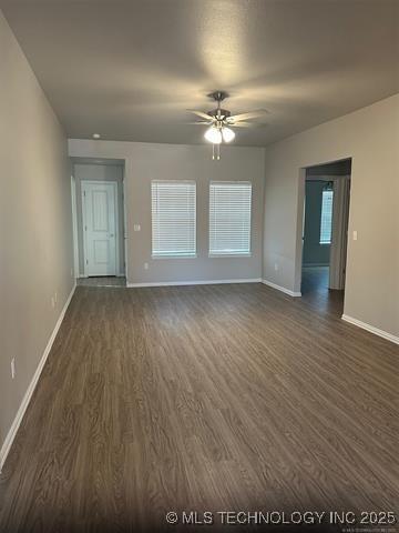 unfurnished living room featuring dark wood-style floors, a ceiling fan, and baseboards