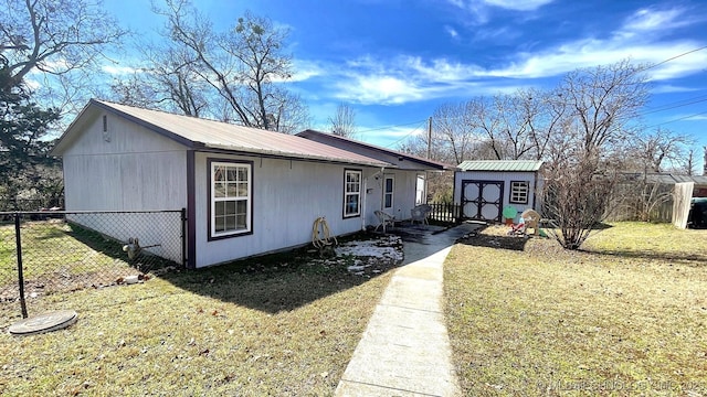 view of front of house featuring a storage shed, metal roof, fence, an outdoor structure, and a front yard