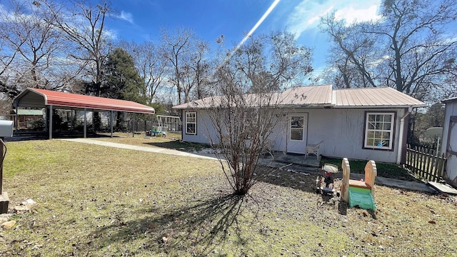 rear view of house featuring metal roof, a lawn, fence, and a detached carport