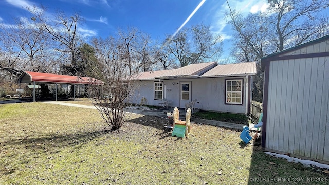 view of front of property featuring a front yard, metal roof, and a detached carport