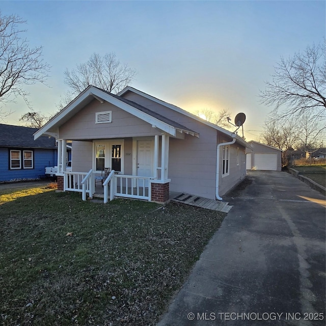 bungalow-style house featuring an outbuilding, covered porch, a detached garage, and a front yard