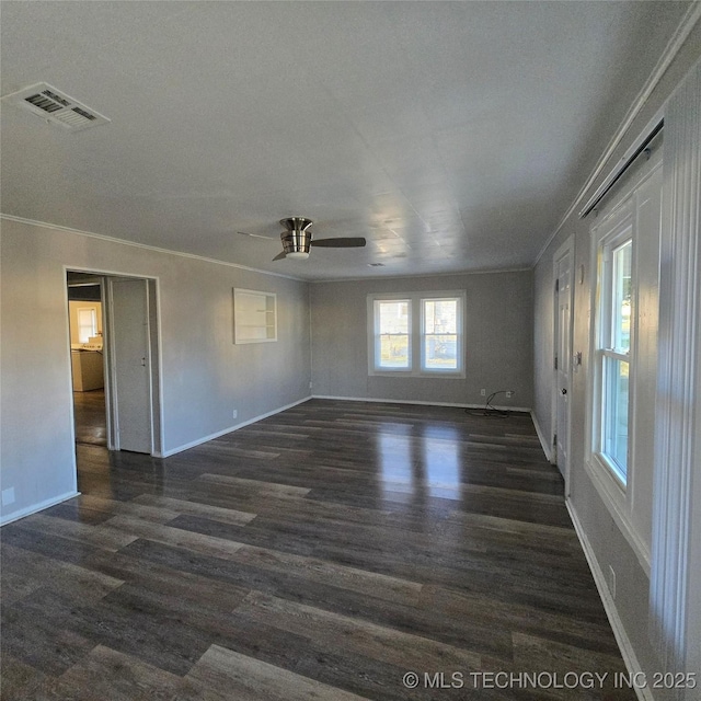 empty room with baseboards, crown molding, visible vents, and dark wood-style flooring