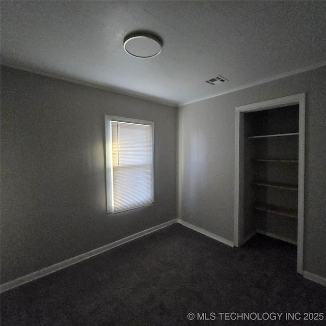 unfurnished bedroom featuring baseboards, visible vents, and dark colored carpet