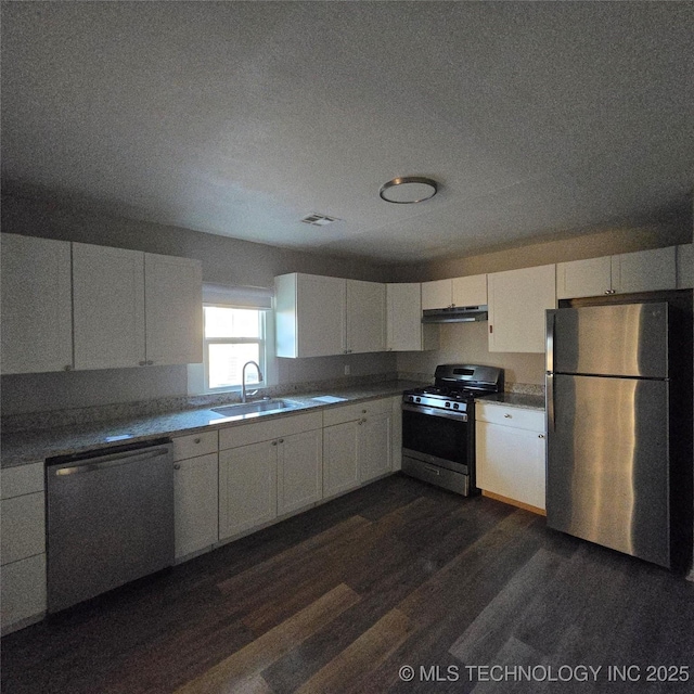 kitchen with appliances with stainless steel finishes, white cabinets, a sink, and under cabinet range hood