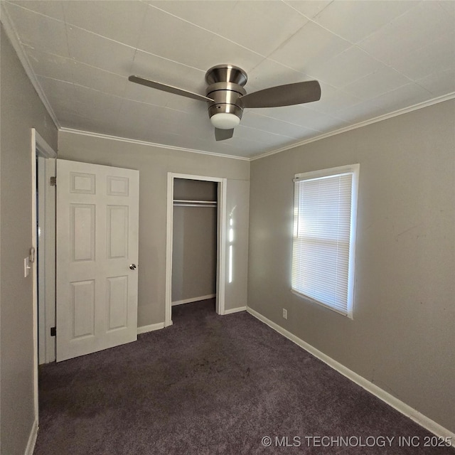 unfurnished bedroom featuring a ceiling fan, baseboards, ornamental molding, a closet, and dark carpet