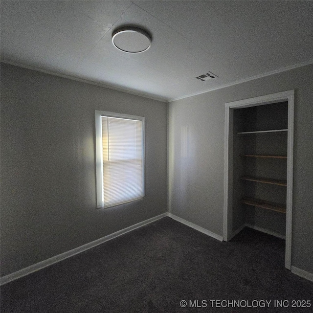 unfurnished bedroom featuring dark colored carpet, visible vents, and baseboards