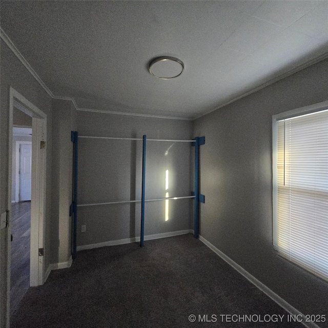 empty room with baseboards, dark carpet, and crown molding