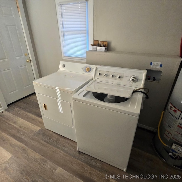 clothes washing area featuring dark wood-style floors, water heater, laundry area, and washer and clothes dryer