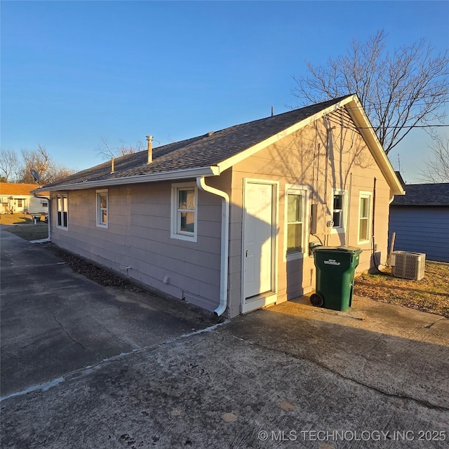 view of home's exterior with roof with shingles and central AC