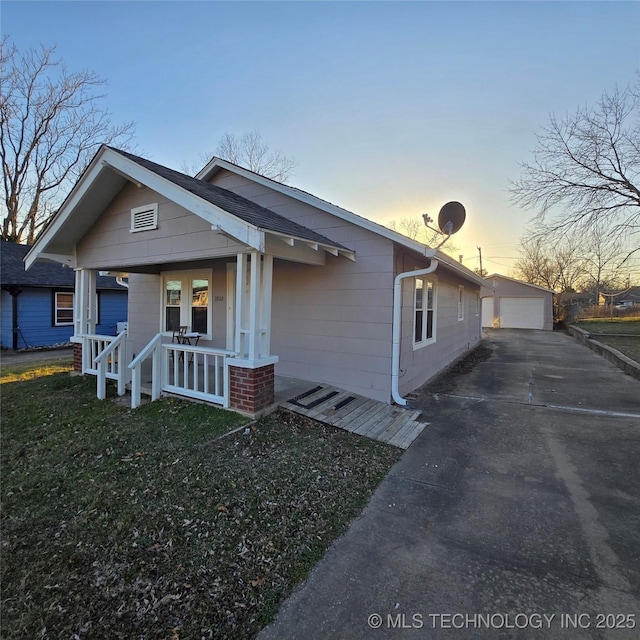 view of front of property with an outbuilding, a porch, a lawn, and a garage