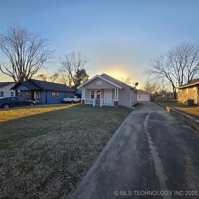 bungalow-style house featuring central air condition unit, a garage, a porch, and a front yard