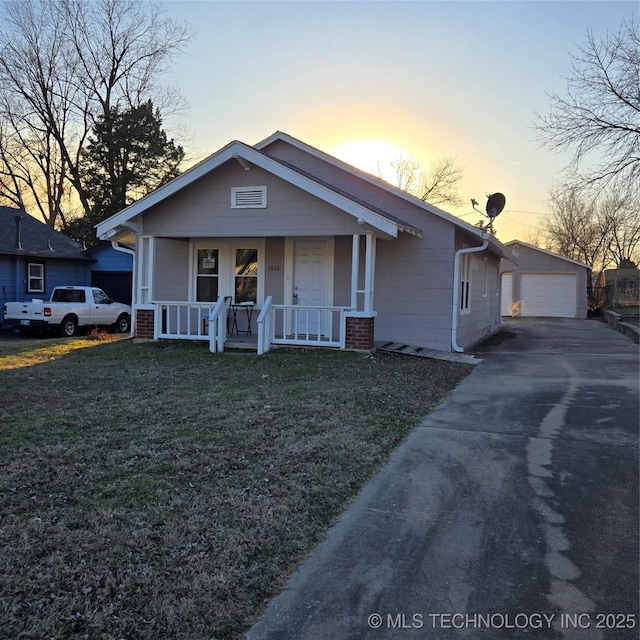 bungalow-style house with an outbuilding, a yard, a porch, and a garage