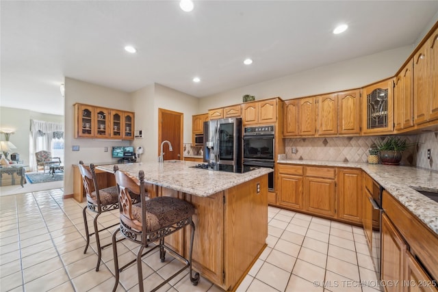 63320 E 293rd Rd, Grove, OK 74344 - kitchen featuring light stone countertops, glass insert cabinets, a kitchen breakfast bar, light tile patterned flooring, and appliances with stainless steel finishes