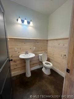 64 Crescent, Ardmore, OK 73401 - half bath featuring wooden walls, toilet, wainscoting, and baseboards