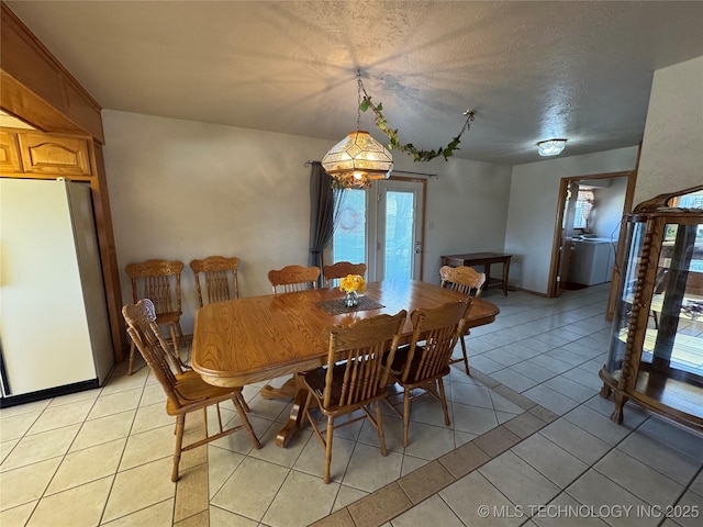 dining space featuring light tile patterned floors, a textured ceiling, and baseboards