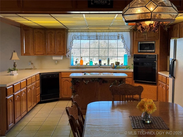 kitchen featuring brown cabinetry, light countertops, black appliances, and light tile patterned floors